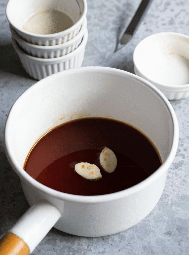 Teriyaki sauce in a white pot with garlic cloves for air fryer chicken