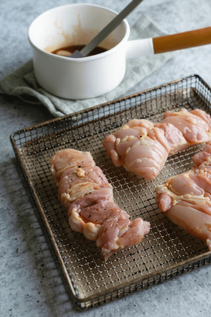 Marinated chicken thighs on air fryer rack with teriyaki sauce in pot